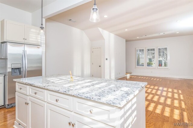 kitchen featuring stainless steel refrigerator with ice dispenser, pendant lighting, white cabinets, light hardwood / wood-style floors, and a kitchen island