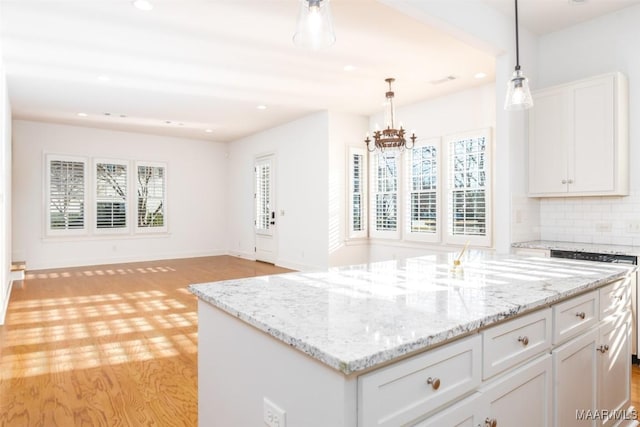 kitchen with tasteful backsplash, a kitchen island, decorative light fixtures, light hardwood / wood-style flooring, and white cabinetry