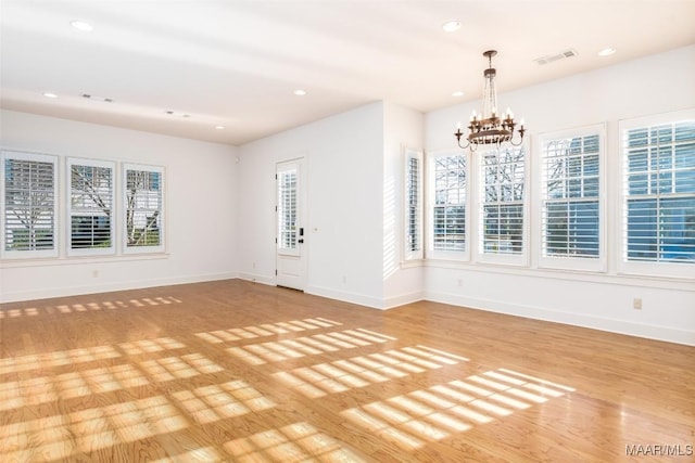 spare room featuring light wood-type flooring and a notable chandelier