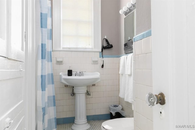 bathroom with tile patterned floors, curtained shower, toilet, and tile walls