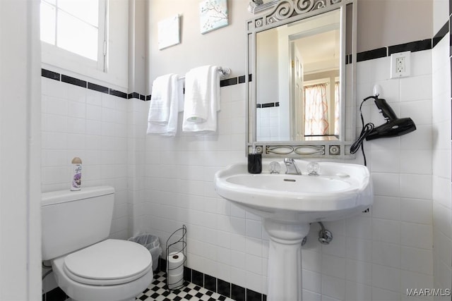 bathroom featuring tile patterned flooring, tile walls, and toilet