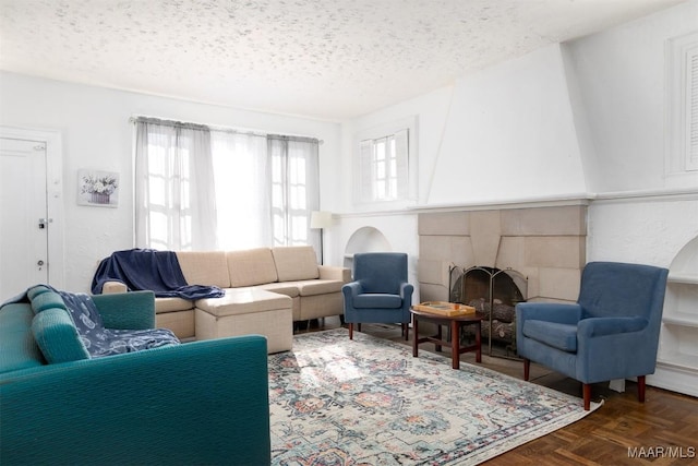 living room with a tile fireplace, dark parquet flooring, and a textured ceiling