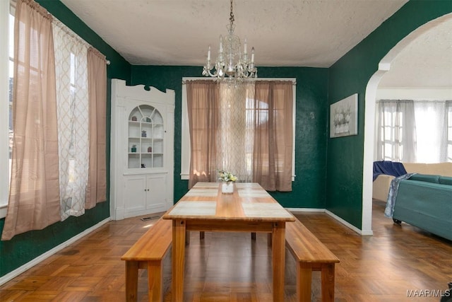 dining area featuring parquet floors, a textured ceiling, and an inviting chandelier