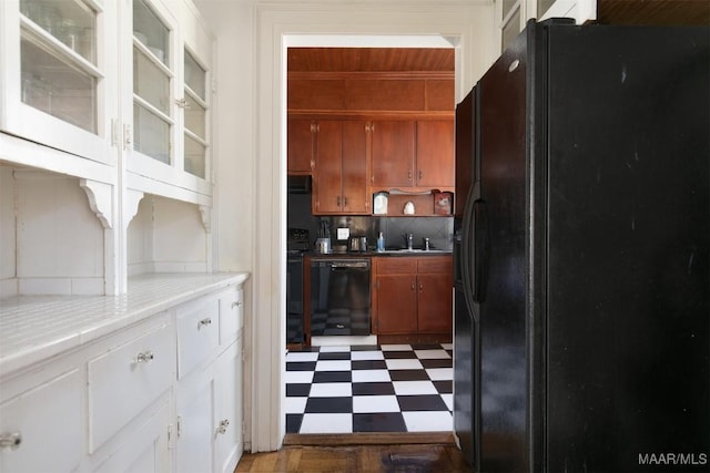 kitchen with backsplash, black appliances, sink, tile counters, and white cabinetry