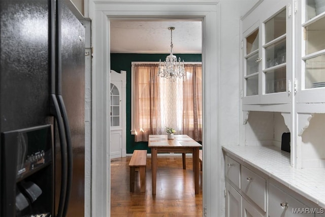 interior space featuring parquet floors, hanging light fixtures, black fridge, a chandelier, and white cabinets