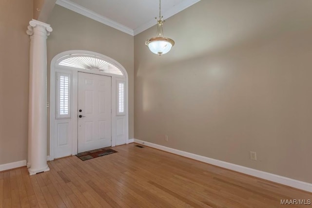 entrance foyer with light hardwood / wood-style floors, ornate columns, ornamental molding, and high vaulted ceiling