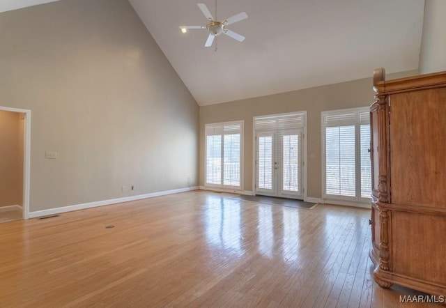 unfurnished living room with ceiling fan, high vaulted ceiling, and light wood-type flooring