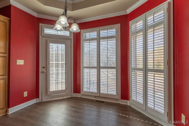 doorway with a chandelier, dark hardwood / wood-style flooring, a raised ceiling, and ornamental molding