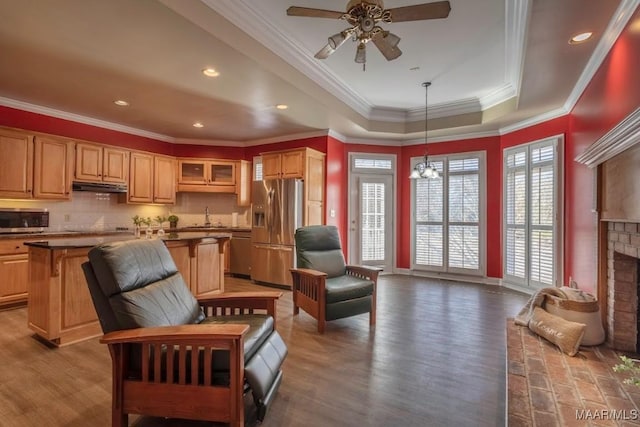 interior space with sink, a raised ceiling, hardwood / wood-style flooring, a fireplace, and ornamental molding