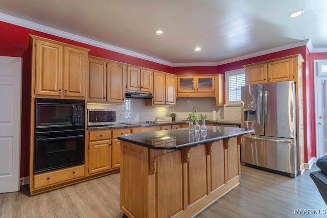 kitchen featuring a center island, black appliances, light hardwood / wood-style flooring, decorative backsplash, and a kitchen bar