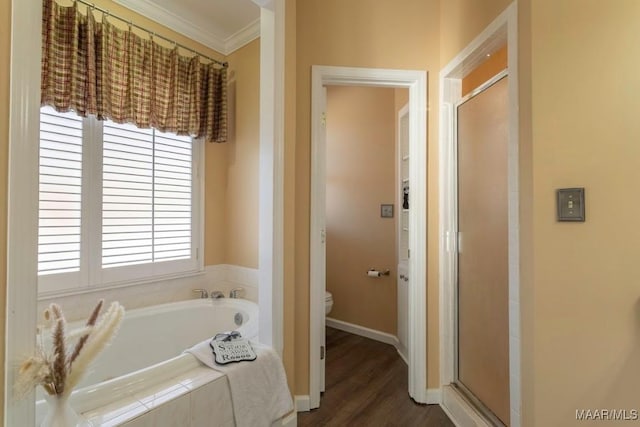 bathroom featuring toilet, wood-type flooring, crown molding, and plus walk in shower