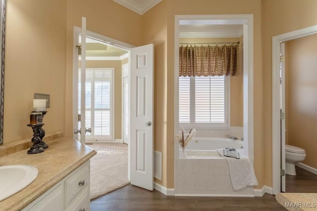 bathroom with vanity, crown molding, a relaxing tiled tub, hardwood / wood-style floors, and toilet