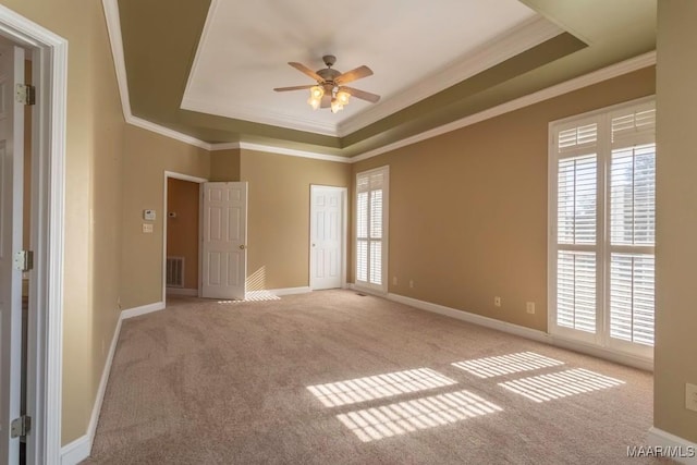 spare room with ceiling fan, light colored carpet, ornamental molding, and a tray ceiling