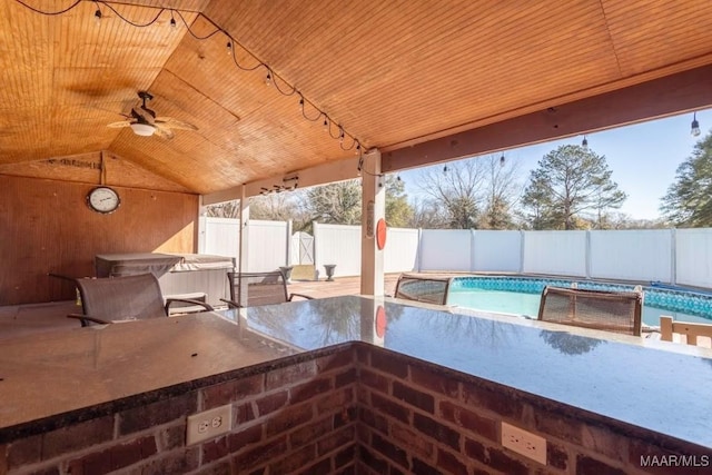 view of patio featuring a fenced in pool, ceiling fan, and exterior bar