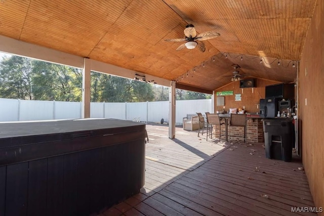 deck featuring ceiling fan, exterior bar, and a hot tub