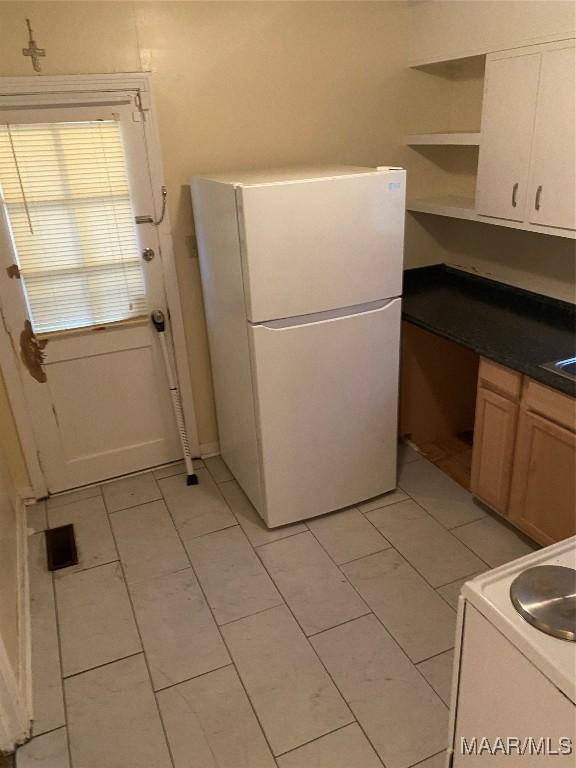 kitchen with white fridge, stove, and light tile patterned floors