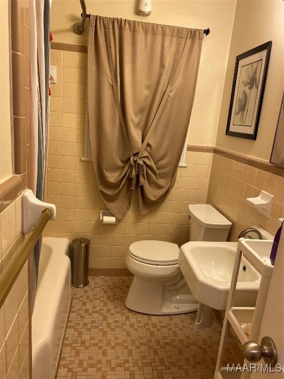 bathroom with toilet and tile walls