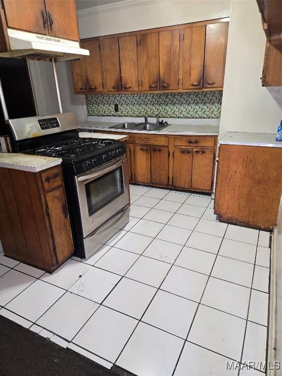 kitchen featuring sink, gas range, decorative backsplash, ornamental molding, and light tile patterned floors