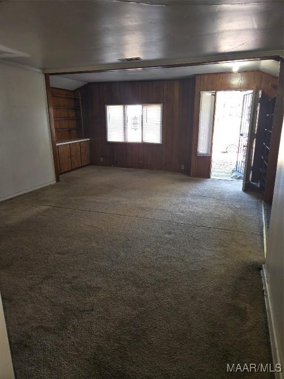 carpeted empty room with a wealth of natural light and wooden walls