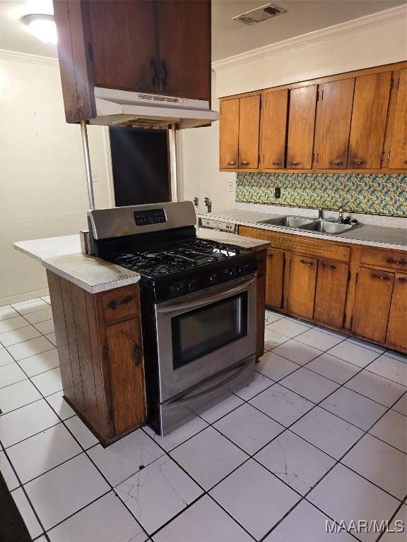 kitchen with gas range, sink, tasteful backsplash, crown molding, and light tile patterned floors