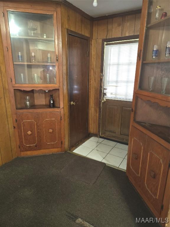 doorway to outside with light tile patterned floors and wooden walls