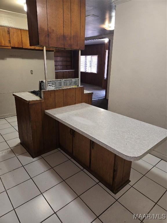 kitchen featuring kitchen peninsula, a kitchen breakfast bar, light tile patterned floors, and crown molding