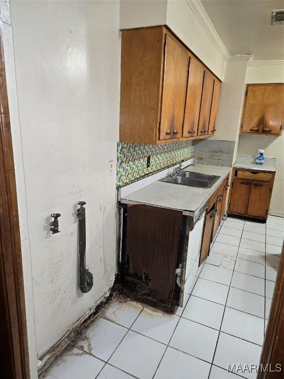 kitchen with backsplash, crown molding, light tile patterned floors, and sink