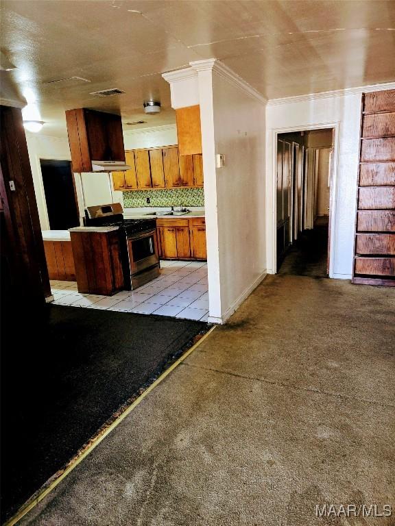 kitchen featuring stove, tasteful backsplash, crown molding, and sink