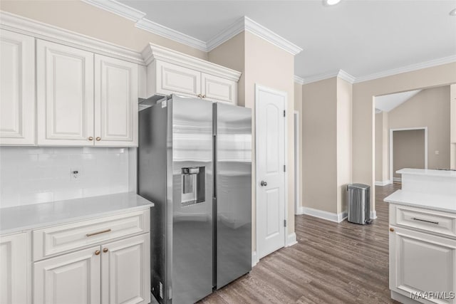 kitchen with hardwood / wood-style floors, backsplash, crown molding, stainless steel fridge with ice dispenser, and white cabinetry