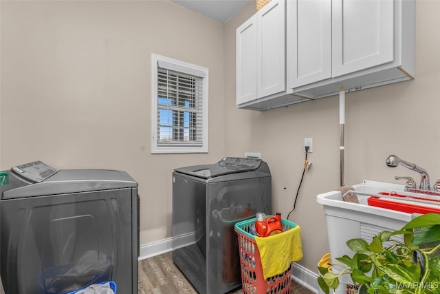 clothes washing area with cabinets, washing machine and dryer, and hardwood / wood-style flooring