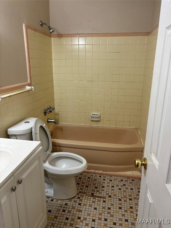 full bathroom featuring tile patterned floors, toilet, vanity, tile walls, and tiled shower / bath