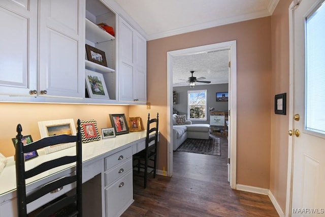 interior space featuring ceiling fan, built in desk, a textured ceiling, ornamental molding, and dark hardwood / wood-style flooring