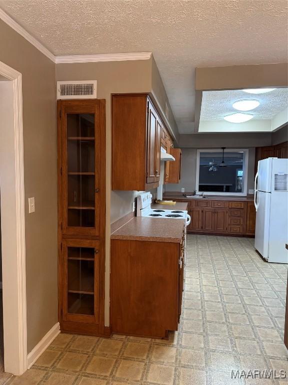 kitchen with a textured ceiling, white appliances, and ornamental molding
