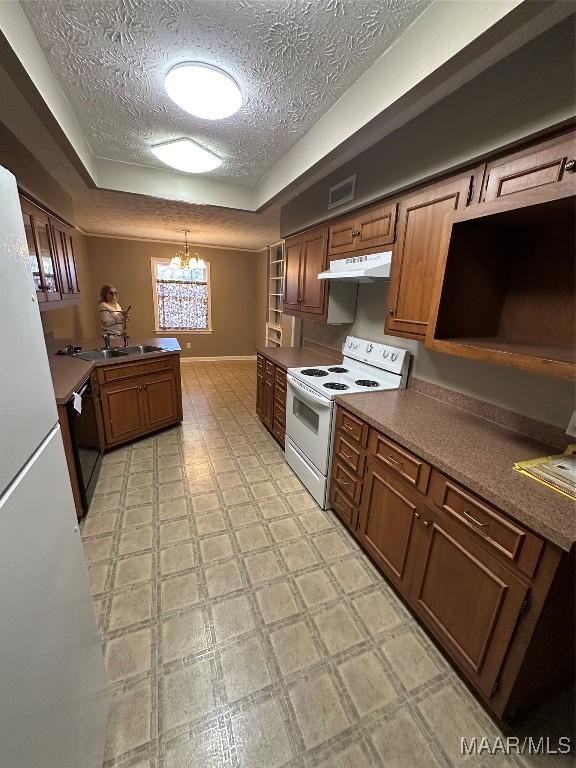 kitchen with kitchen peninsula, a chandelier, a textured ceiling, decorative light fixtures, and white appliances