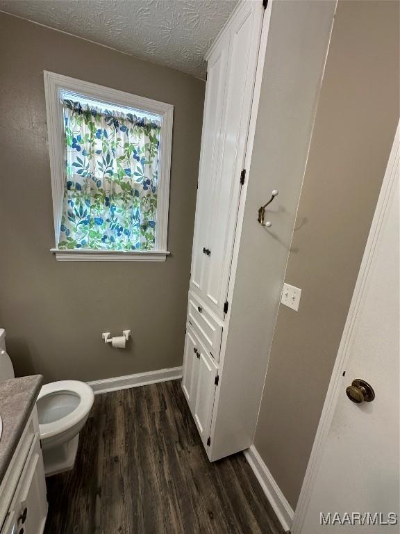 bathroom with toilet, vanity, a textured ceiling, and hardwood / wood-style flooring