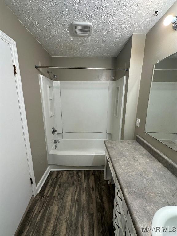 bathroom featuring vanity, shower / bathing tub combination, wood-type flooring, and a textured ceiling