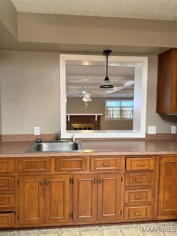 kitchen with a fireplace, sink, pendant lighting, and a textured ceiling