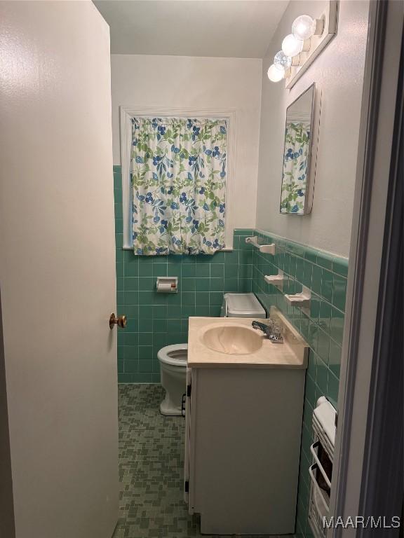 bathroom featuring tile patterned floors, vanity, toilet, and tile walls