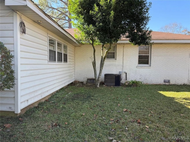 view of side of property with a yard and central AC