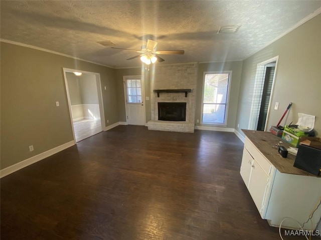 unfurnished living room with ceiling fan, a textured ceiling, a wealth of natural light, and a brick fireplace