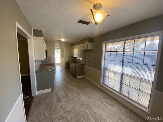 kitchen with a textured ceiling, light stone counters, and sink