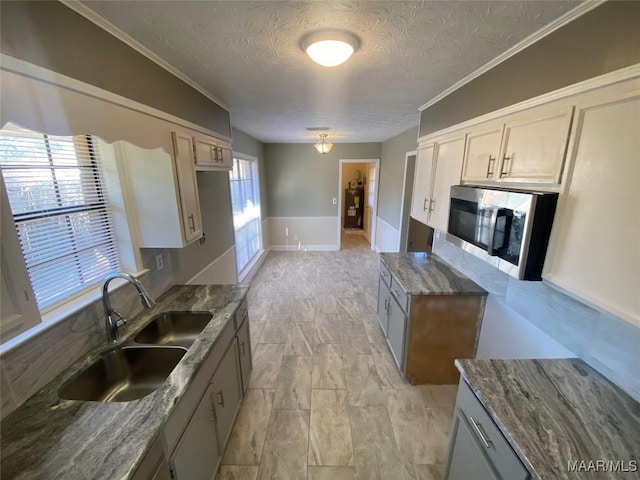 kitchen featuring a textured ceiling, plenty of natural light, dark stone counters, and sink