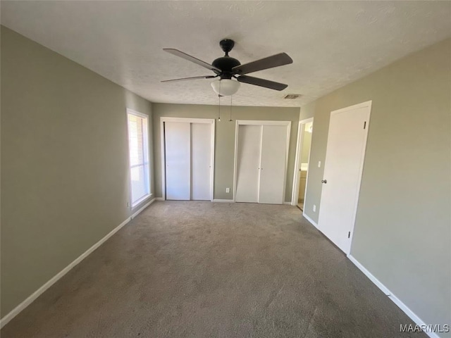 unfurnished bedroom featuring multiple closets, ceiling fan, and carpet floors