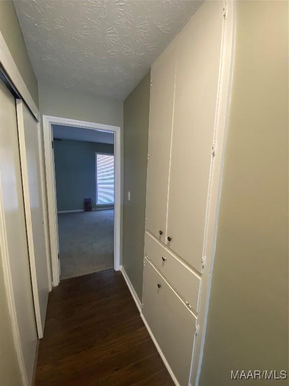 hallway featuring a textured ceiling and dark hardwood / wood-style flooring