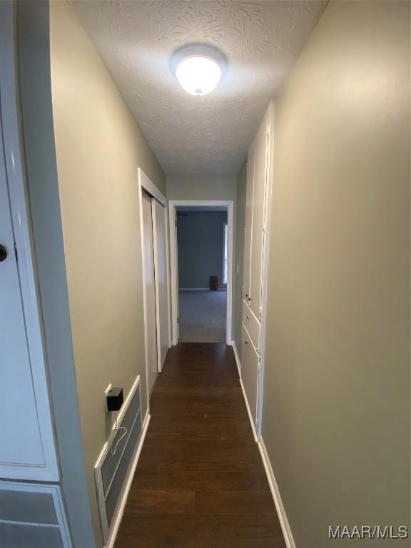 hallway with a textured ceiling and dark wood-type flooring