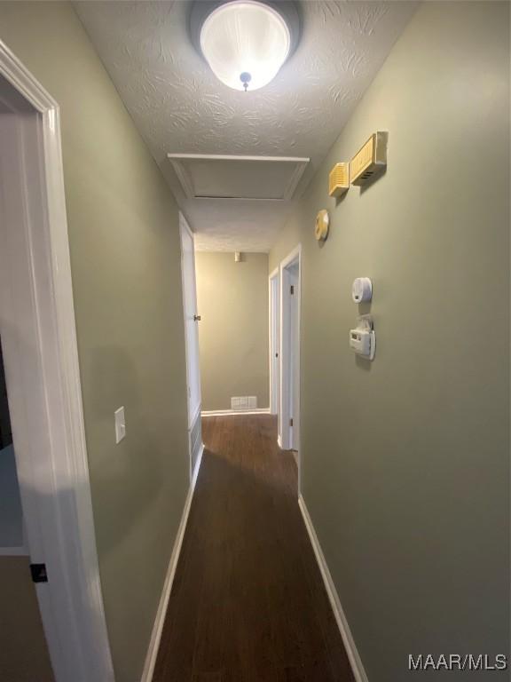 hall featuring a textured ceiling and dark hardwood / wood-style floors