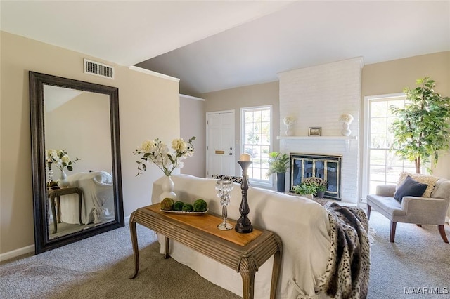 living room with carpet, vaulted ceiling, a wealth of natural light, and a brick fireplace