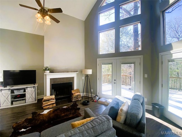 living room featuring a fireplace, french doors, a towering ceiling, and hardwood / wood-style flooring