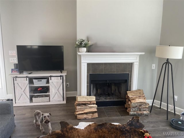 living room featuring a tile fireplace and dark hardwood / wood-style floors