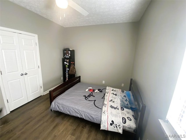 bedroom featuring ceiling fan, a closet, dark hardwood / wood-style floors, and a textured ceiling